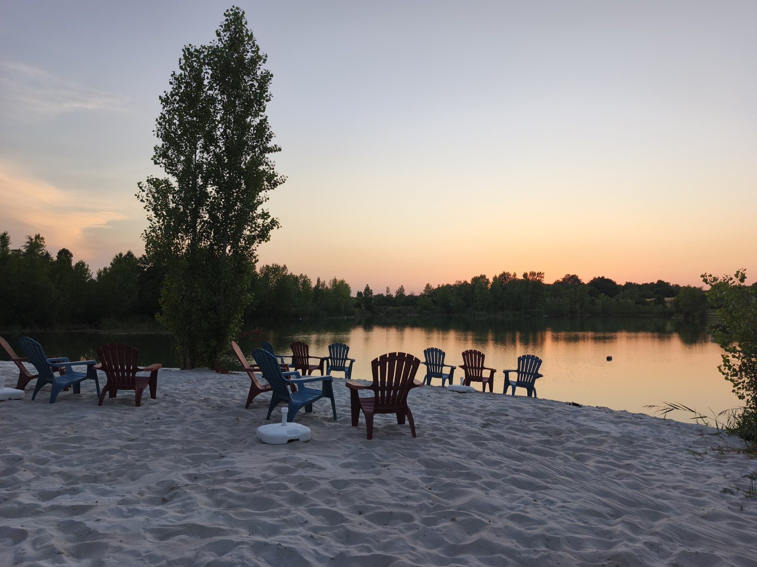 Coucher de soleil sur le lac et fauteuils sur le sable